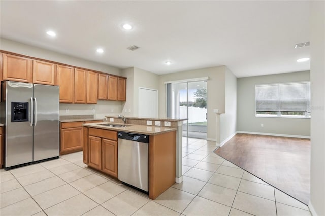 kitchen with a wealth of natural light, appliances with stainless steel finishes, sink, and light tile patterned floors