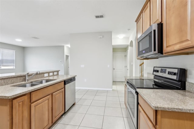 kitchen with light stone counters, sink, stainless steel appliances, and light tile patterned flooring