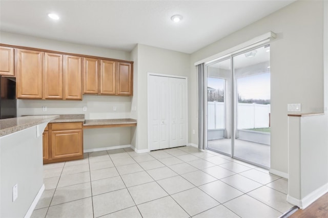 kitchen with refrigerator, light stone countertops, and light tile patterned floors