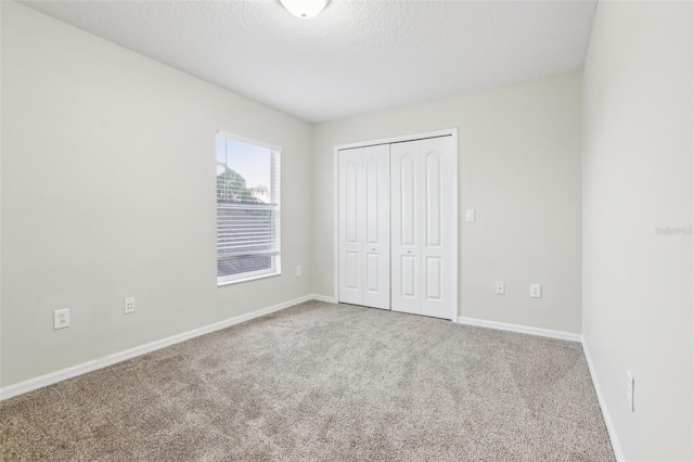 unfurnished bedroom featuring carpet floors, a closet, and a textured ceiling