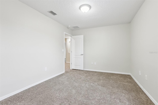 empty room with carpet floors and a textured ceiling