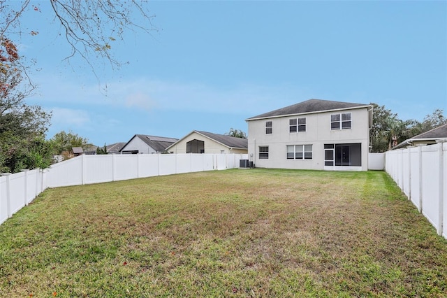 rear view of property featuring a yard and central AC unit