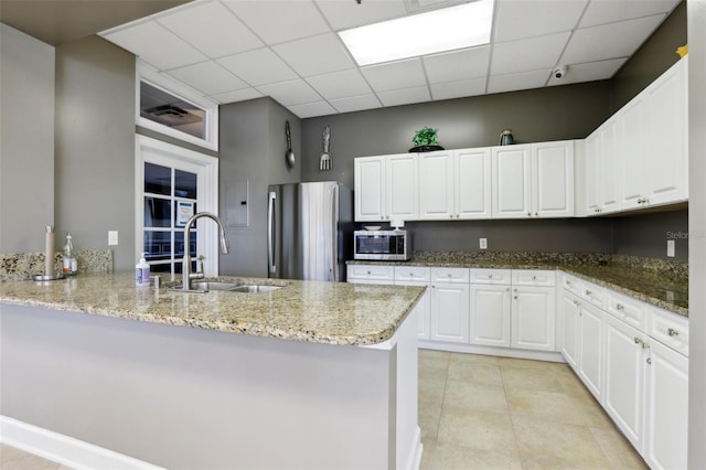 kitchen with white cabinetry, appliances with stainless steel finishes, sink, and light stone counters