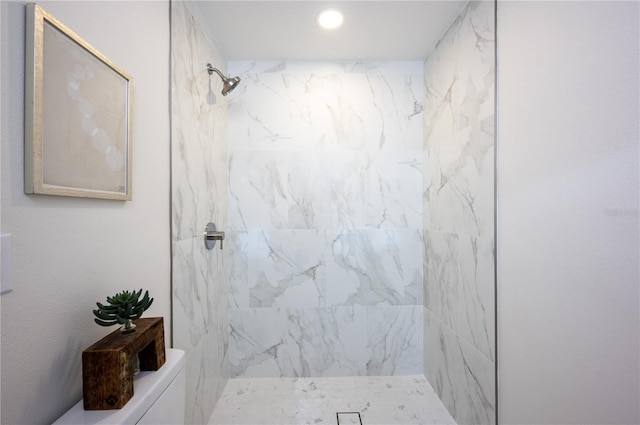 bathroom featuring a tile shower and toilet