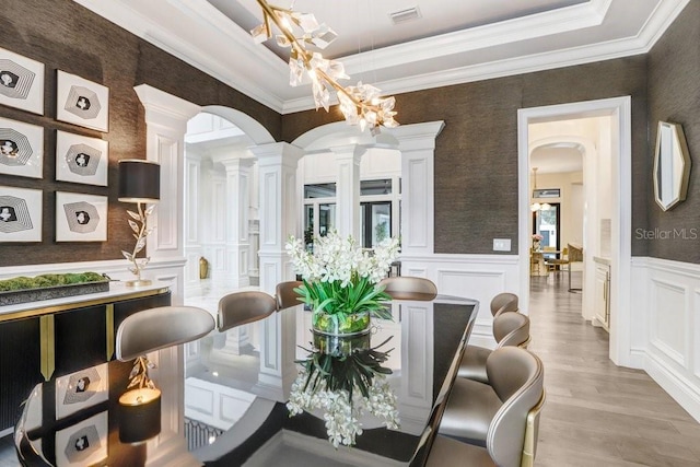 dining area with decorative columns, ornamental molding, and light hardwood / wood-style floors