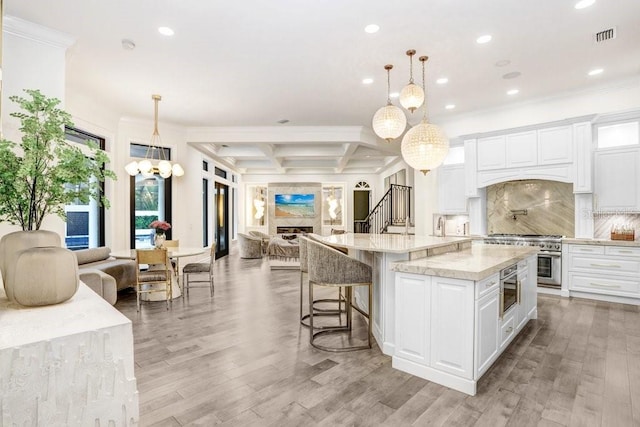 kitchen featuring high end stainless steel range oven, white cabinetry, coffered ceiling, a kitchen island, and decorative light fixtures