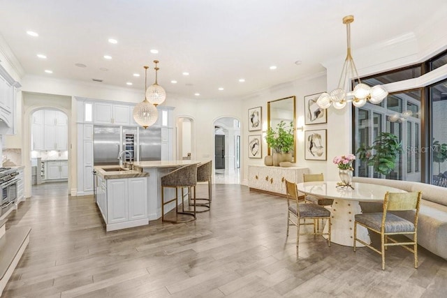 kitchen featuring a center island with sink, sink, hanging light fixtures, and white cabinets