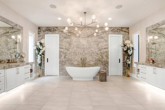 bathroom with tile patterned flooring, vanity, a washtub, and a chandelier