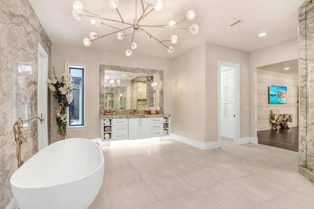 bathroom with an inviting chandelier, vanity, tile patterned flooring, and a washtub