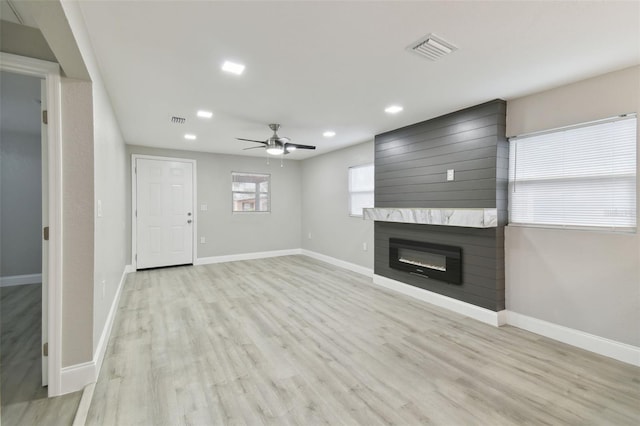 unfurnished living room with a fireplace, ceiling fan, and light wood-type flooring