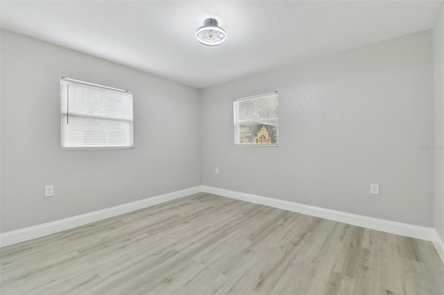 unfurnished room with light wood-type flooring and baseboards