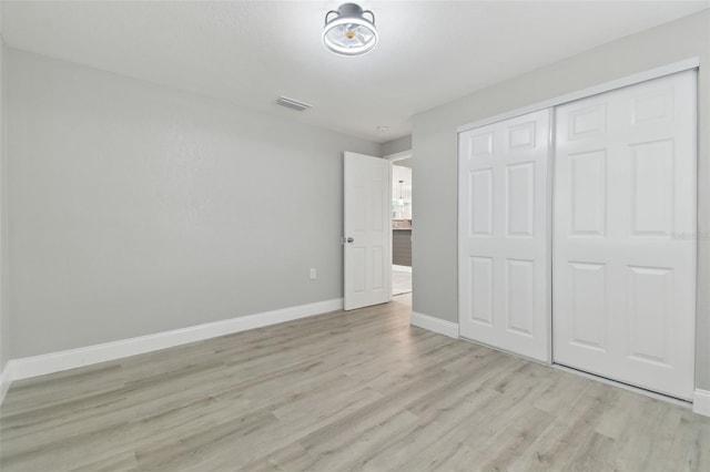 unfurnished bedroom with a closet, baseboards, visible vents, and light wood finished floors