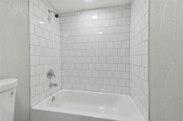 full bathroom featuring toilet, bathing tub / shower combination, and a textured wall