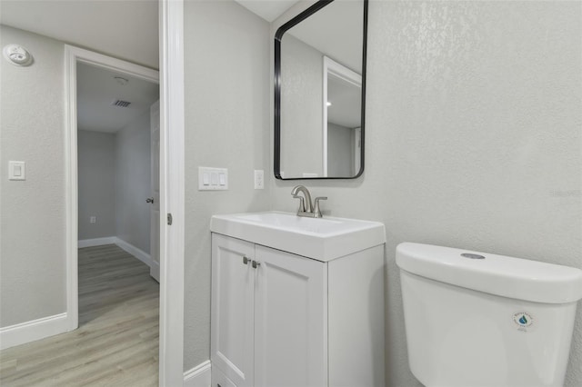 bathroom with wood-type flooring, toilet, and vanity