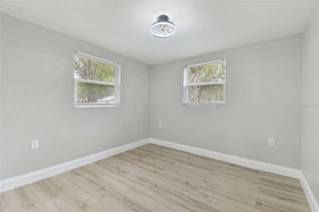 empty room with light wood-style flooring and baseboards