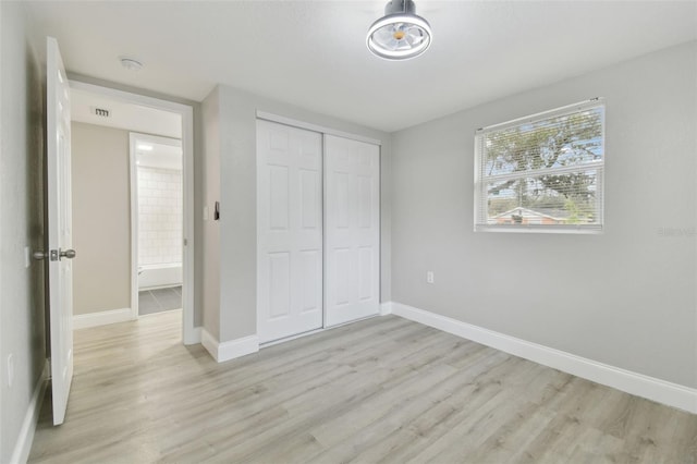 unfurnished bedroom featuring light wood finished floors, visible vents, a closet, and baseboards