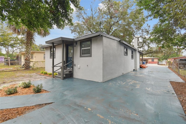 exterior space featuring a patio, fence, driveway, and stucco siding