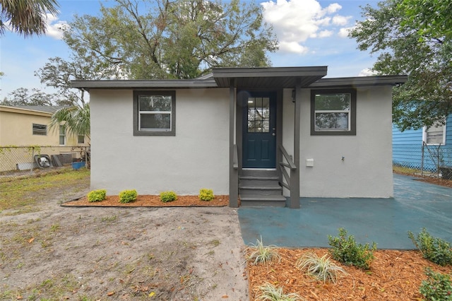 view of front facade with stucco siding, fence, and entry steps