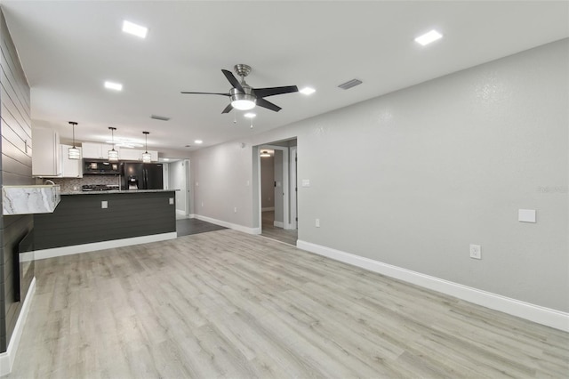 unfurnished living room featuring light wood finished floors, visible vents, ceiling fan, and baseboards