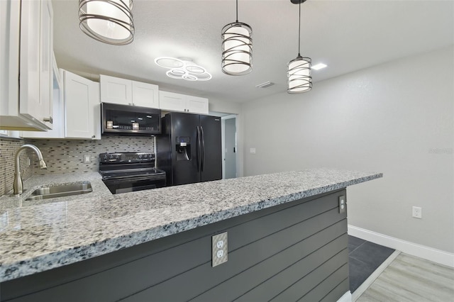 kitchen featuring light stone countertops, a sink, decorative backsplash, black appliances, and white cabinetry