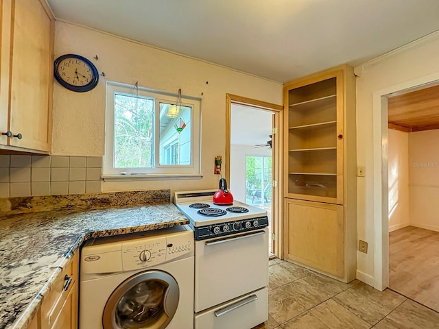 kitchen with a wealth of natural light, washer / clothes dryer, white electric stove, backsplash, and dark stone counters