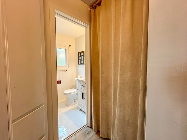 bathroom with vanity, hardwood / wood-style floors, toilet, and tile walls