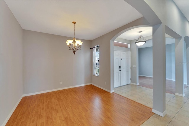 spare room with light tile patterned flooring and a notable chandelier