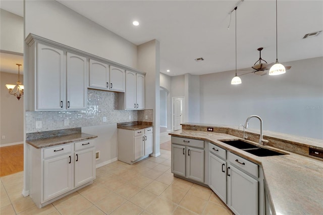 kitchen featuring decorative backsplash, sink, hanging light fixtures, and light tile patterned floors