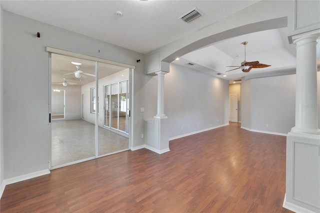 unfurnished living room with dark wood-type flooring, ceiling fan, and ornate columns