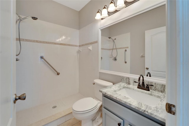 bathroom with vanity, tile patterned floors, toilet, and tiled shower