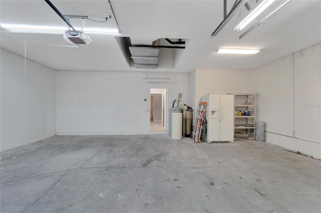 garage featuring a garage door opener, white refrigerator with ice dispenser, and water heater