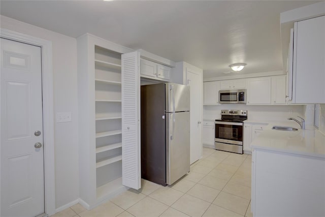 kitchen featuring white cabinetry, stainless steel appliances, light tile patterned flooring, and sink