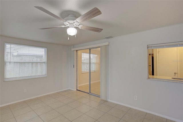 tiled spare room featuring ceiling fan and a healthy amount of sunlight