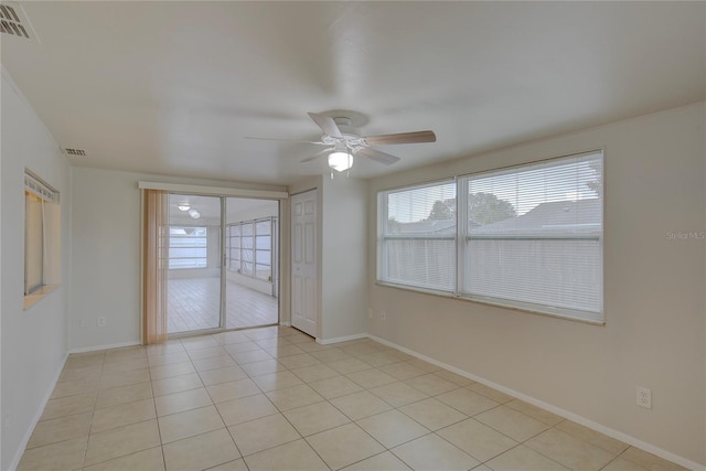 tiled spare room featuring ceiling fan and a healthy amount of sunlight