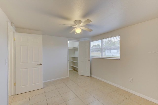 unfurnished bedroom featuring a spacious closet, light tile patterned floors, ceiling fan, and a closet