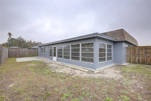 rear view of house featuring a patio, a sunroom, and a lawn