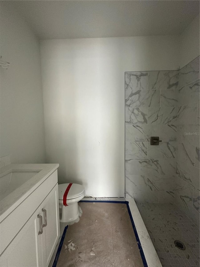 bathroom featuring tiled shower, vanity, and toilet