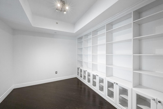 unfurnished room with built in shelves, a notable chandelier, wood finished floors, baseboards, and a raised ceiling