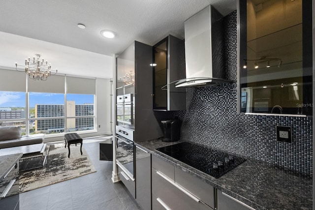 kitchen featuring modern cabinets, oven, black electric cooktop, wall chimney range hood, and backsplash