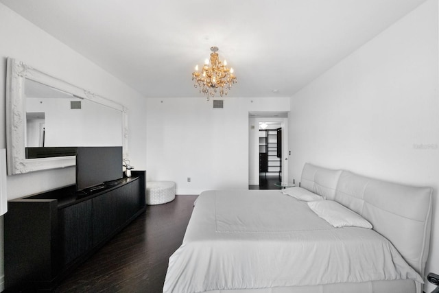 bedroom with wood finished floors, visible vents, and a notable chandelier