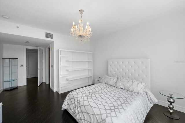 bedroom featuring an inviting chandelier, visible vents, baseboards, and wood finished floors