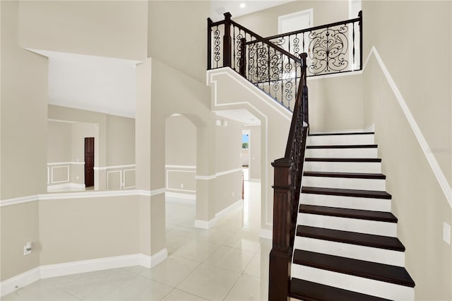 stairway with a towering ceiling and tile patterned floors