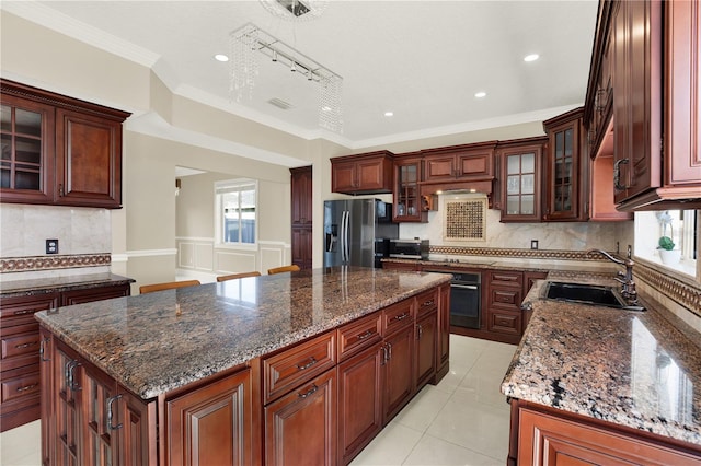 kitchen with sink, rail lighting, appliances with stainless steel finishes, dark stone countertops, and a kitchen island