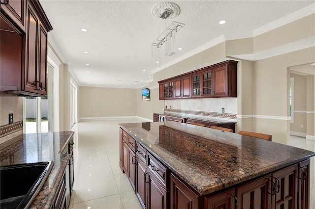 kitchen featuring sink, a textured ceiling, light tile patterned floors, a kitchen island, and pendant lighting