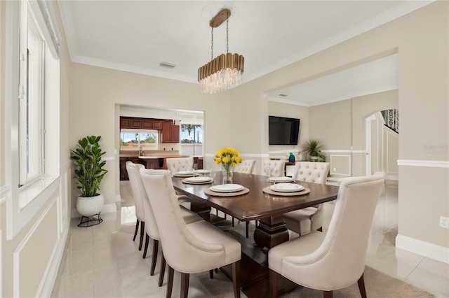 dining space with light tile patterned flooring, crown molding, and a notable chandelier