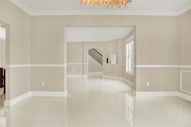 spare room with ornamental molding, light tile patterned flooring, and a notable chandelier