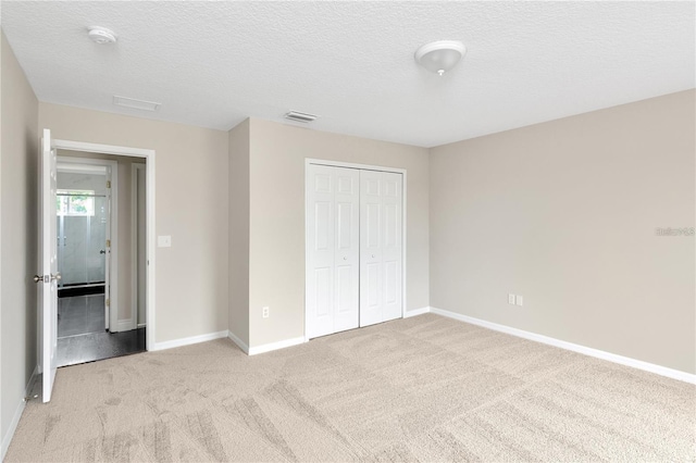 unfurnished bedroom with light carpet, a textured ceiling, and a closet