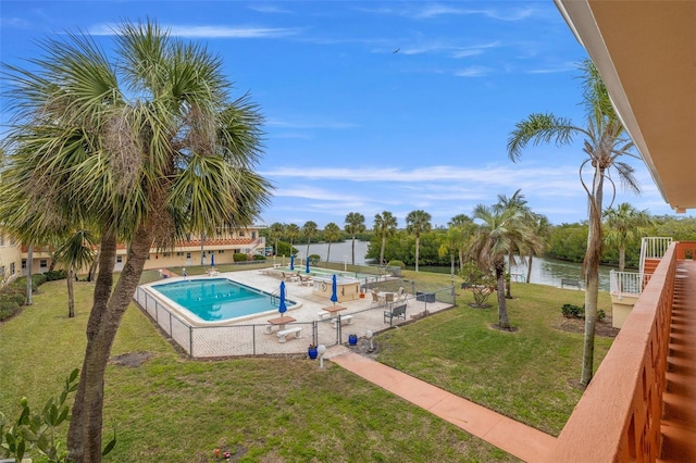 view of pool with a water view and a lawn