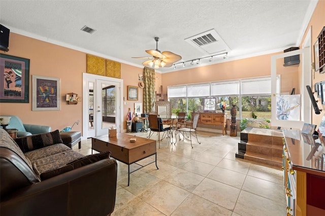 living room featuring light tile patterned floors, crown molding, ceiling fan, track lighting, and a textured ceiling