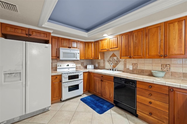 kitchen with sink, backsplash, tile counters, a raised ceiling, and white appliances